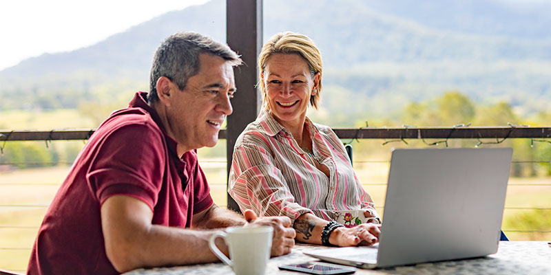 Middle aged couple sitting together looking at laptop screen