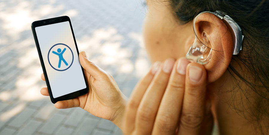 Image of a hearing impaired woman with a phone displaying the accessibility icon