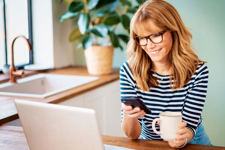 Lady looking at phone and laptop