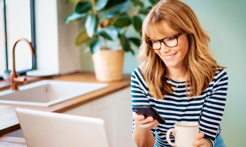 Lady looking at phone and laptop